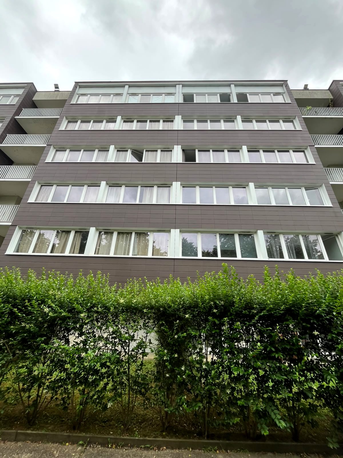 Façade de la résidence en contre-plongée : bandeaux vitrés filants sur cinq niveaux.