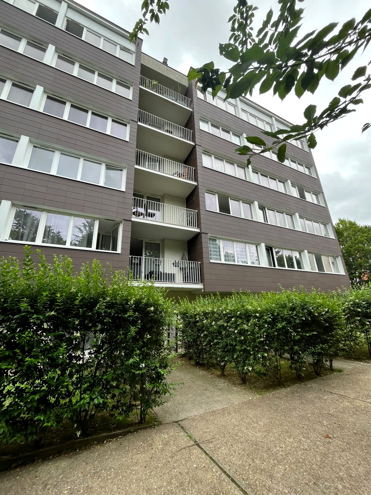 Vue d'ensemble du bâtiment après rénovation énergétique, balcons en cage centrale.
