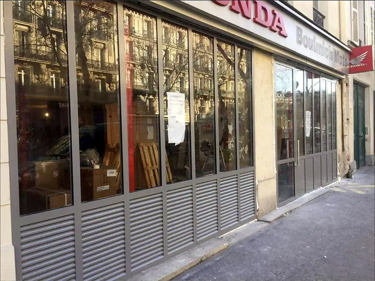 Vitrines de la concession vues en enfilade, châssis acier et soubassements ventilés.