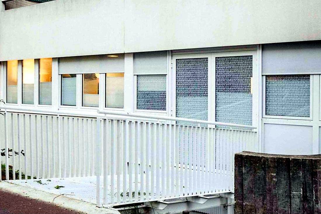 Garde-corps barreaudé et main courante tubulaire devant un ensemble menuisé en rez-de-chaussée.