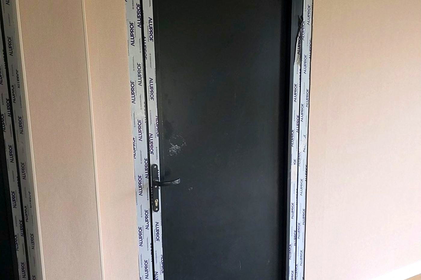 Porte aluminium à un vantail avec ferme-porte en applique, béquille et cylindre montés.